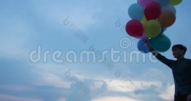 年轻夫妇<strong>拿</strong>着<strong>气球</strong>和日落背景。